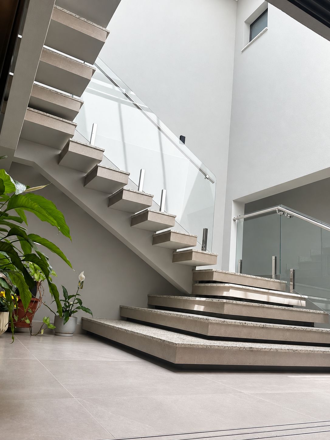 Escada em pedra e vidro no hall da clínica, com luz natural